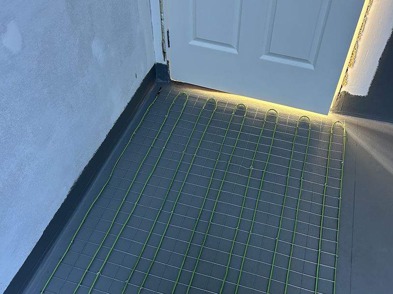 Electric heating cable laid across a bathroom floor before tiling